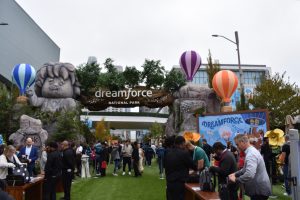 Attendees enter the 2023 Dreamforce National Park under a tree log supported by carved rock characters.